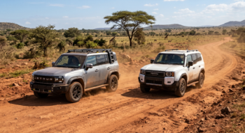 A side-by-side comparison of a silver Jetour T2 and a white Toyota Prado driving on a dusty, unpaved red dirt road in an African savanna landscape with sparse acacia trees and wildlife in the background.
