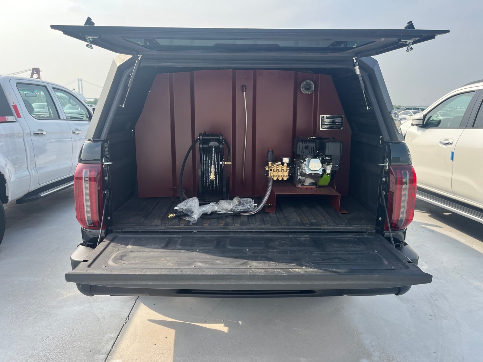 Custom pickup truck bed installation featuring a professional high-pressure washer unit, hose reel, and auxiliary tank for mobile cleaning services.