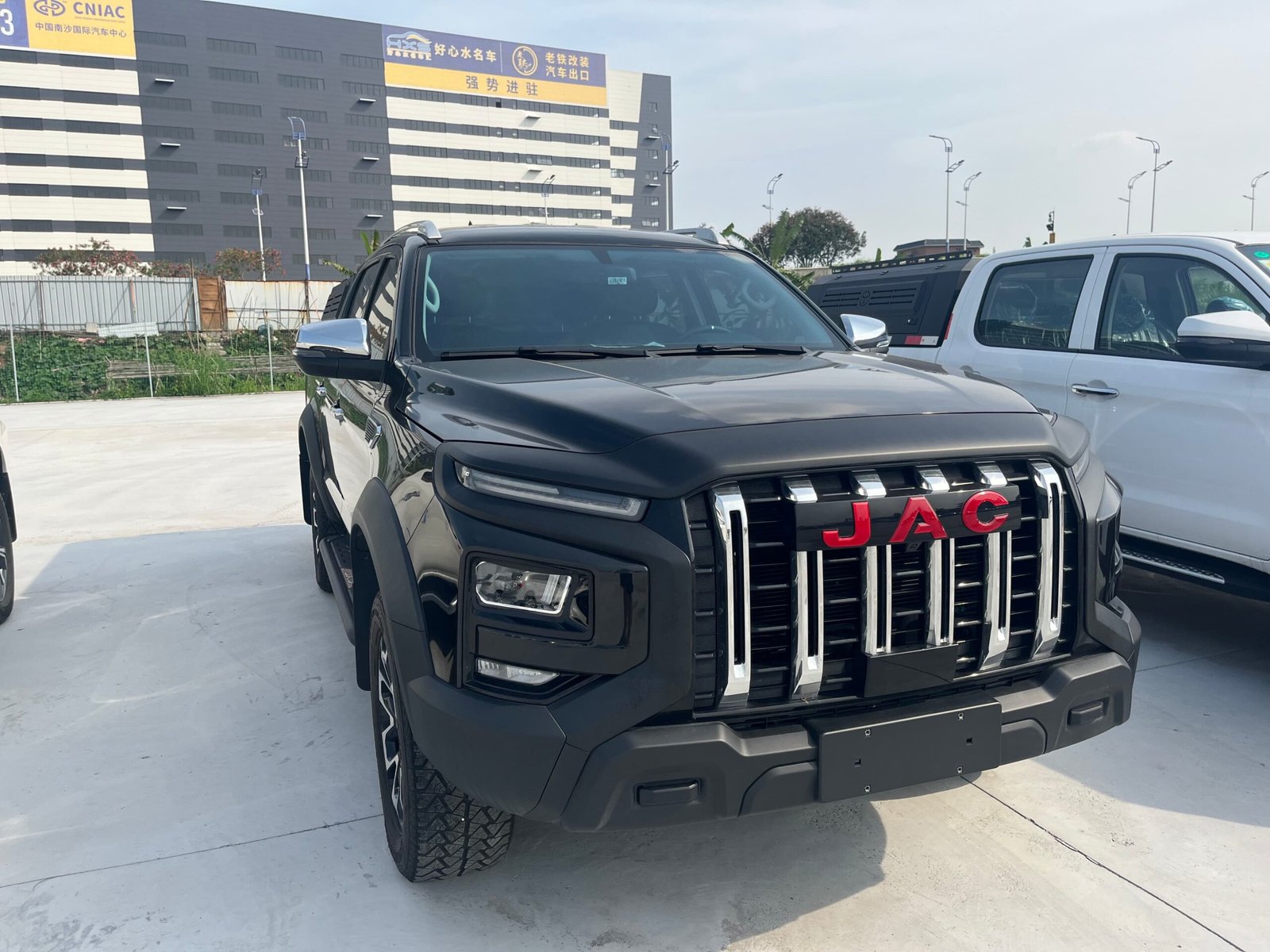 Powerful black JAC off-road pickup truck with vertical chrome grille bars and rugged all-terrain tires.