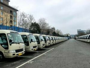 Front view of three beige used Toyota Coaster minibuses parked in a row. These units are from a premium Chinese tourism fleet, featuring original Toyota logos and clean, well-maintained exteriors. The photo highlights the ready-for-export condition of these 23-30 seater passenger buses in our Shenzhen inventory.