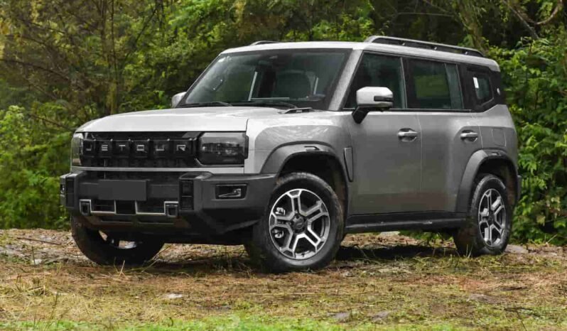 Front three-quarter view of Jetour T2 Traveler SUV showing the JETOUR grille, square headlights, rugged front bumper, alloy wheels and outdoor forest background