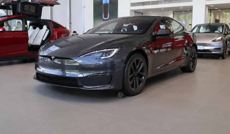 Front three-quarter view of Tesla Model S 2023 dual motor all-wheel drive grey electric sedan showing sleek body design, LED headlights, black wheels and showroom display